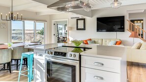 Een moderne keuken met een ingebouwde kookplaat, witte kasten en een groot eiland.