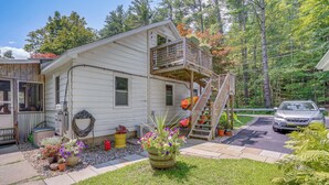 Une maison de plain-pied avec un porche à l’avant, une petite terrasse et un escalier menant à un balcon situé à l’étage.