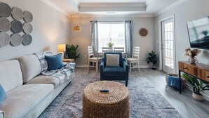 Un salon comprenant un canapé, une table basse, un téléviseur et un coin repas avec des chaises et une table.