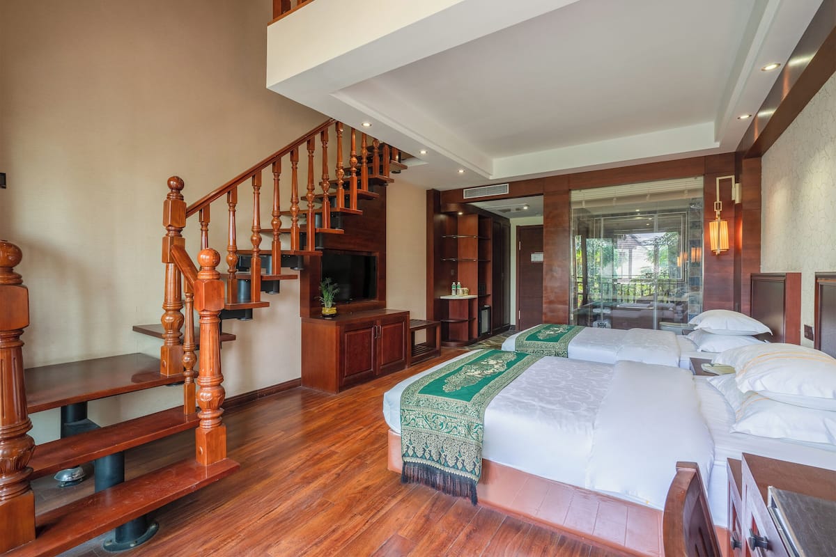A spacious bedroom with a large bed, a wooden staircase, and a TV.