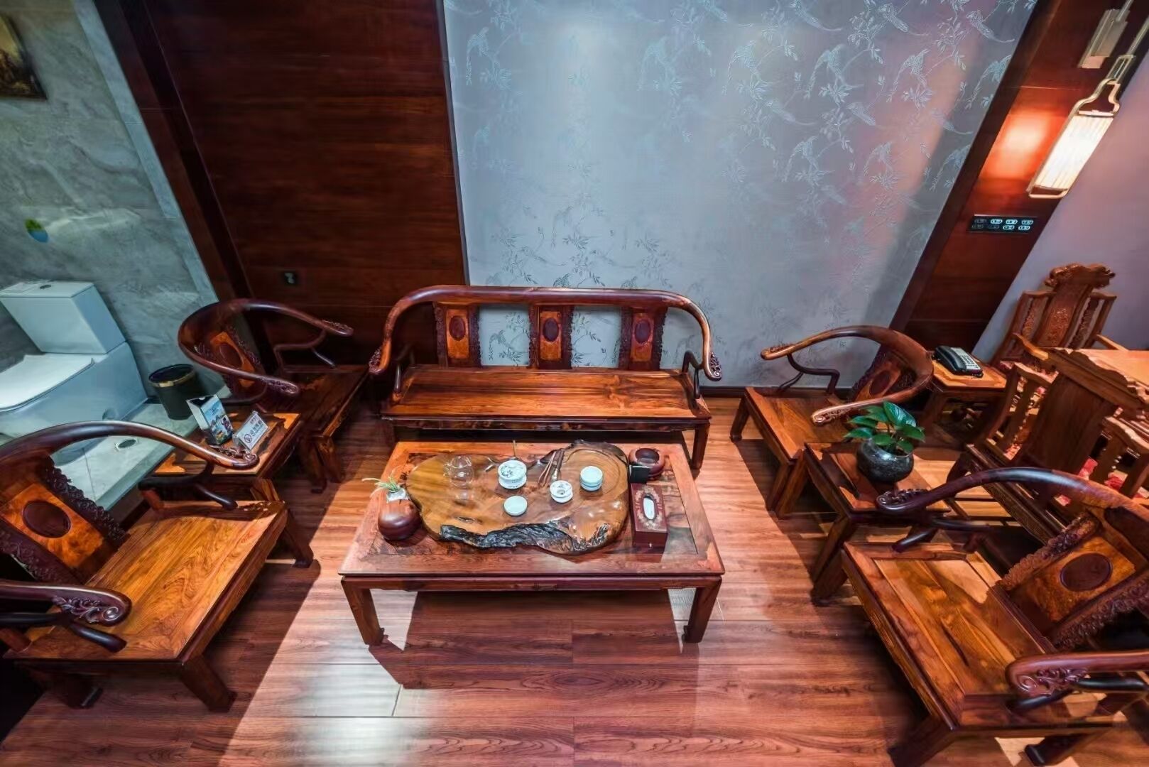 A traditional wooden room with a central sofa, side tables, and chairs.