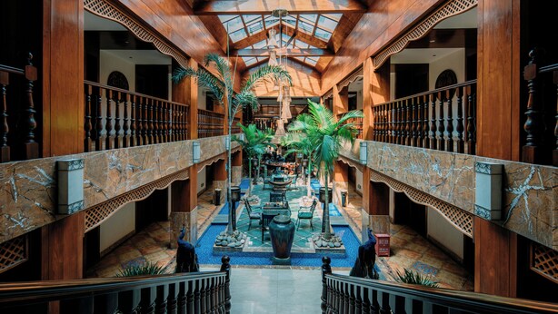 A spacious atrium with a high ceiling, wooden railings, and a central fountain. - XiShuangBanNa BaoYu Vaction Hotel (Xishuangbanna Dai)