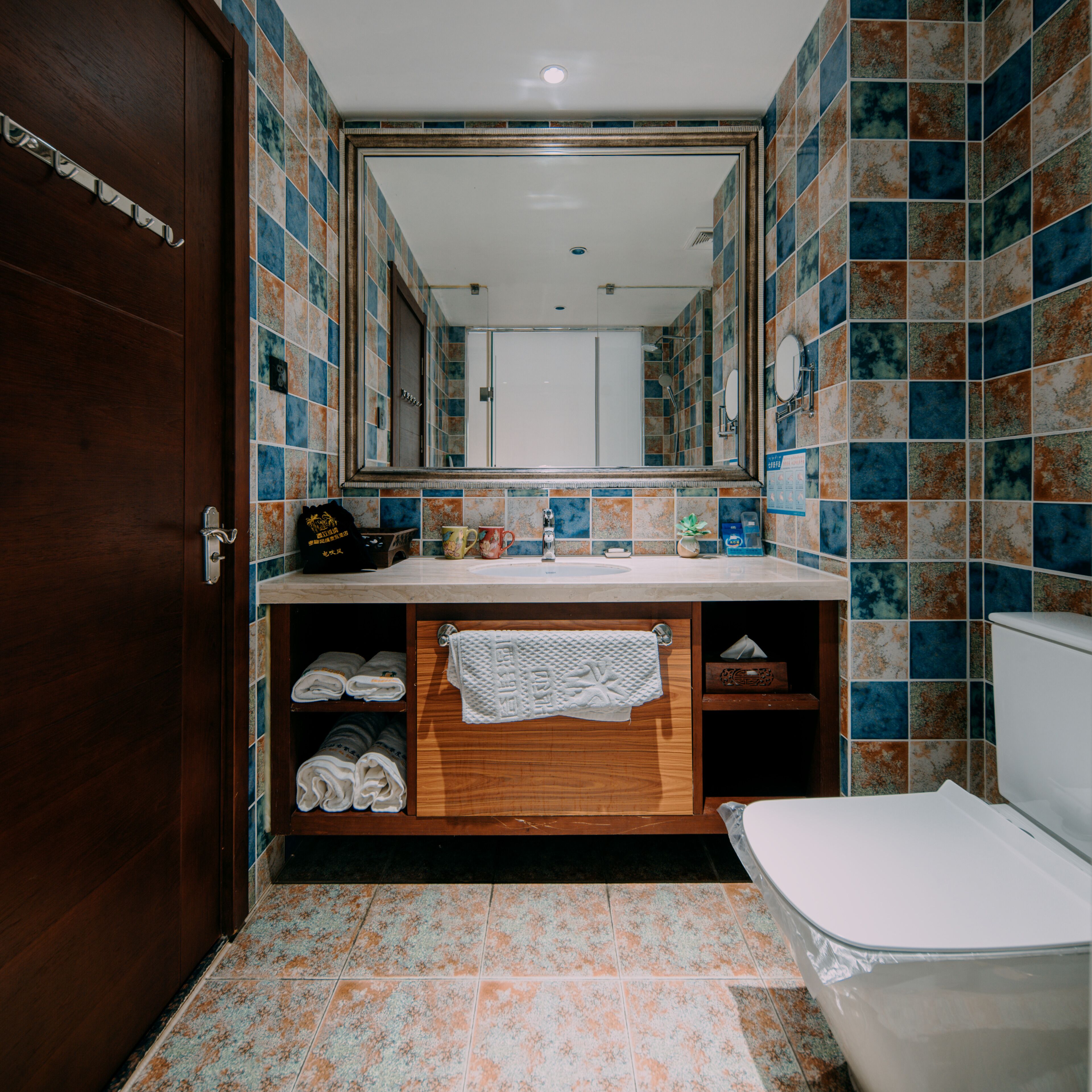 Ein Badezimmer mit Holztür, Waschbecken und einem Spiegel darüber sowie Toilette.