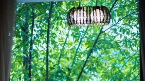 A balcony with wicker chairs, a glass table, and a hanging light fixture. - XiShuangBanNa BaoYu Vaction Hotel (Xishuangbanna Dai)