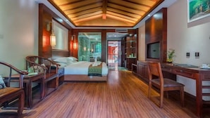 A spacious hotel room with a large bed, wooden furniture, a desk, and a TV. - XiShuangBanNa BaoYu Vaction Hotel (Xishuangbanna Dai)