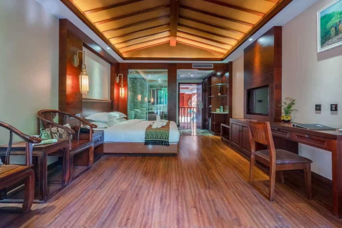 A spacious hotel room with a large bed, wooden furniture, a desk, and a TV.