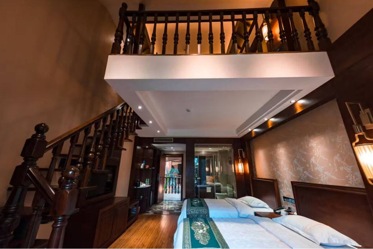 A hotel room with a balcony, a staircase, and a view of the outdoors.