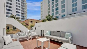 A rooftop terrace with white furniture, including sofas and chairs, and a small white table. - Steps to Beach Studio Suite | Pool & Las Olas (Fort Lauderdale)