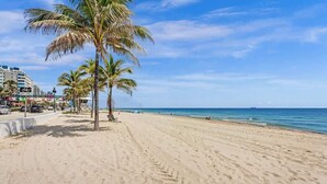 A beach with palm trees, a bike lane, and a view of the ocean. - Eden 1BR | Steps to Fort Lauderdale Beach (Fort Lauderdale)