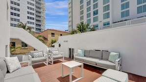 A rooftop terrace with white furniture, including sofas and chairs, and a small white table. - Eden 1BR | Steps to Fort Lauderdale Beach (Fort Lauderdale)
