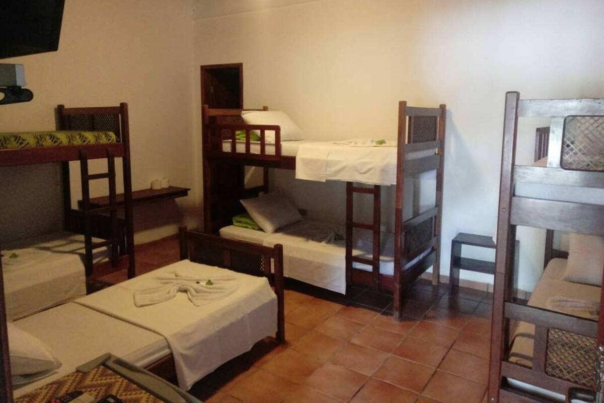 A dormitory room with bunk beds, a small table, and a chair.