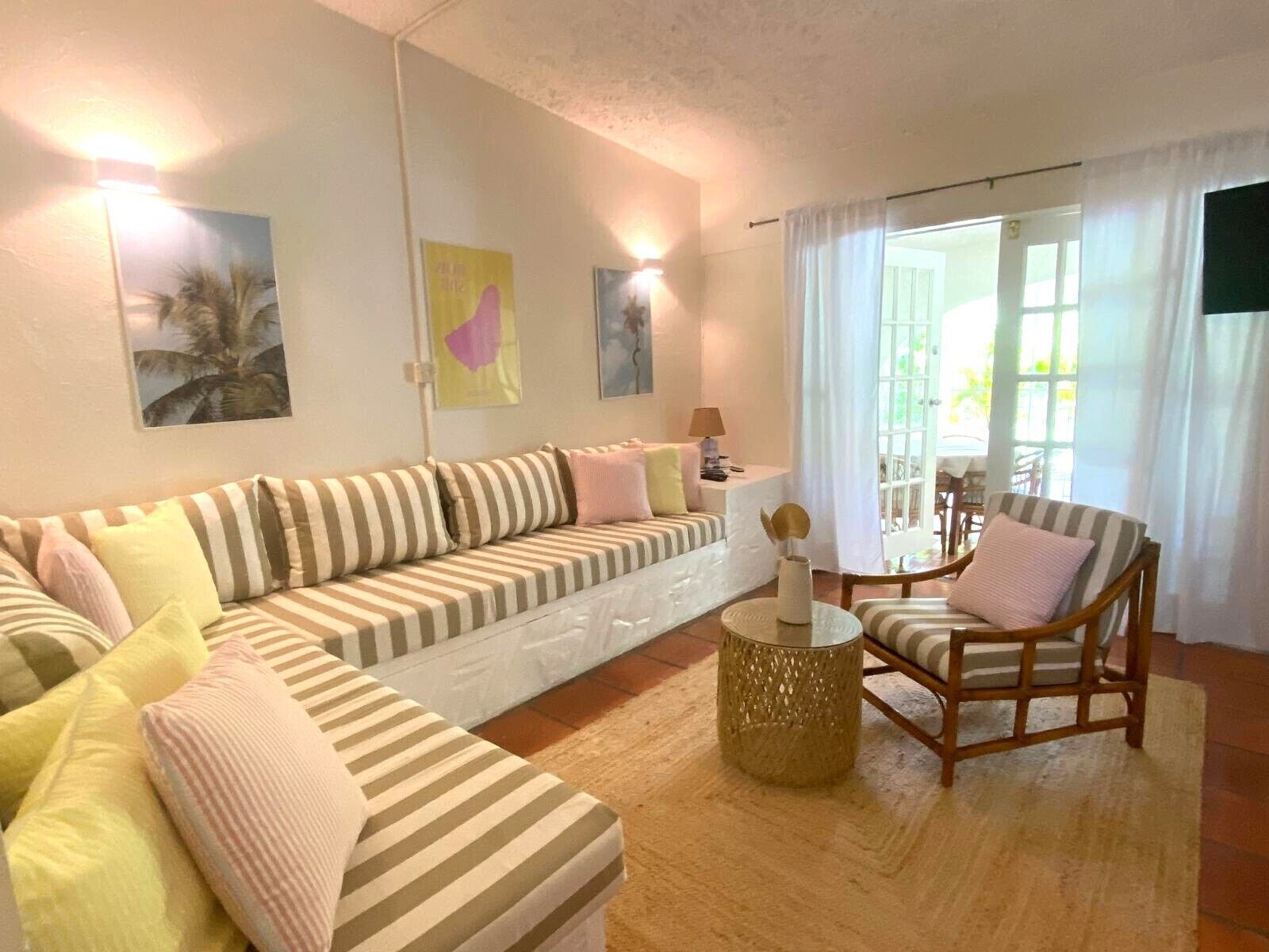 A living room with a striped sofa, a wooden chair, and a small table with a vase.