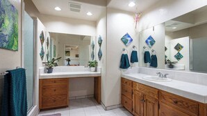 Un baño moderno con un lavamanos blanco, armarios de madera y un espejo grande.