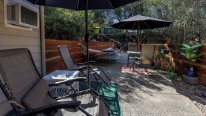 Un patio con mobiliario exterior, incluyendo sillas y una mesa, bajo un paraguas grande.