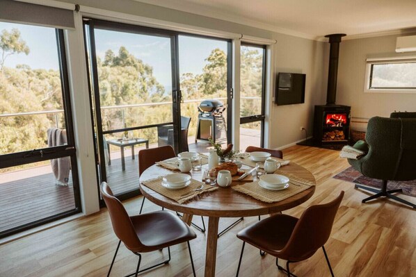 A dining area with a table set for four, surrounded by large windows offering a view of the outdoors.