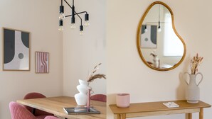 Un coin repas avec une table en bois, des chaises roses, un vase blanc contenant des plantes séchées et une tasse rose.