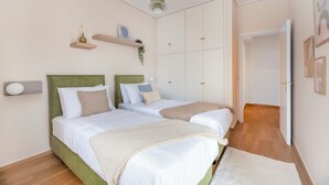 Une chambre avec deux lits, un plancher en bois et une armoire à plusieurs portes.