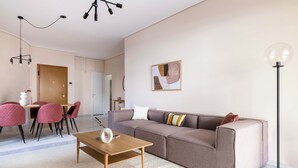 Un salon moderne avec un canapé d’angle, une table basse en bois et un coin repas avec des chaises rouges.
