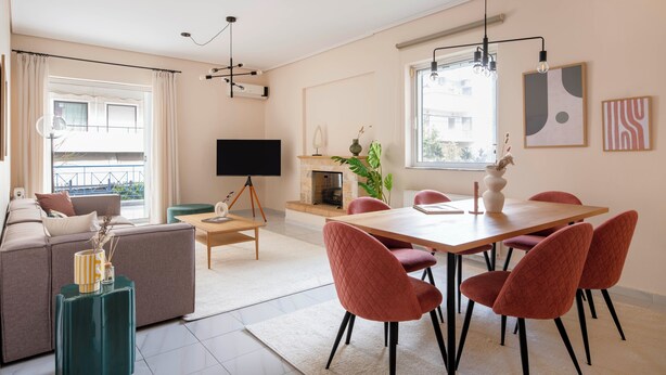 Un salon moderne comprenant un canapé, une table à manger avec des chaises, un téléviseur, une cheminée et des œuvres d’art accrochées aux murs.
