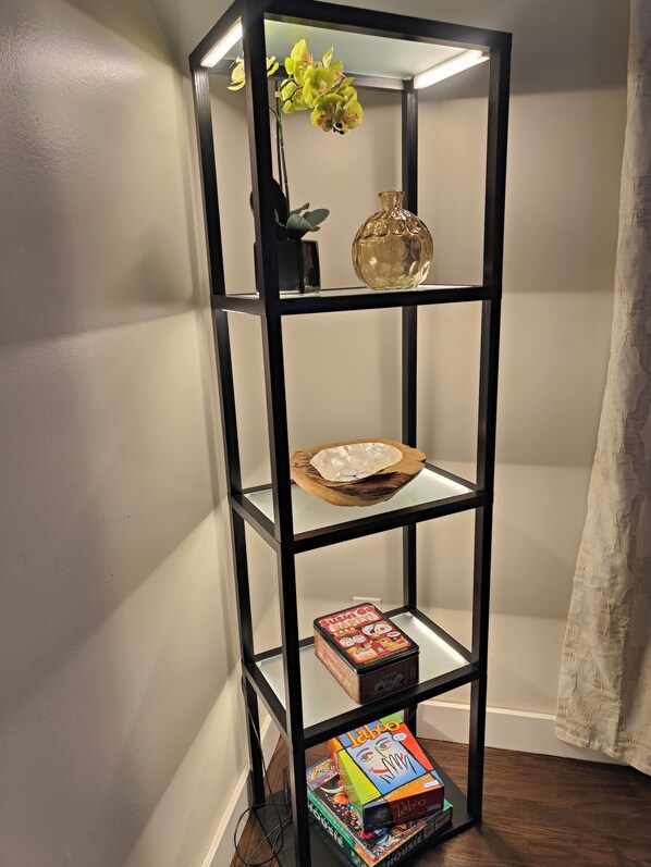A black metal shelf unit with glass doors, containing a vase, a bowl, and a box of Laboo puzzle games. - 5BR 4BA - Waterfront, Hot-tub, Pool table, Kayaks, Fire tables. luxeatlouise.com (Tacoma)