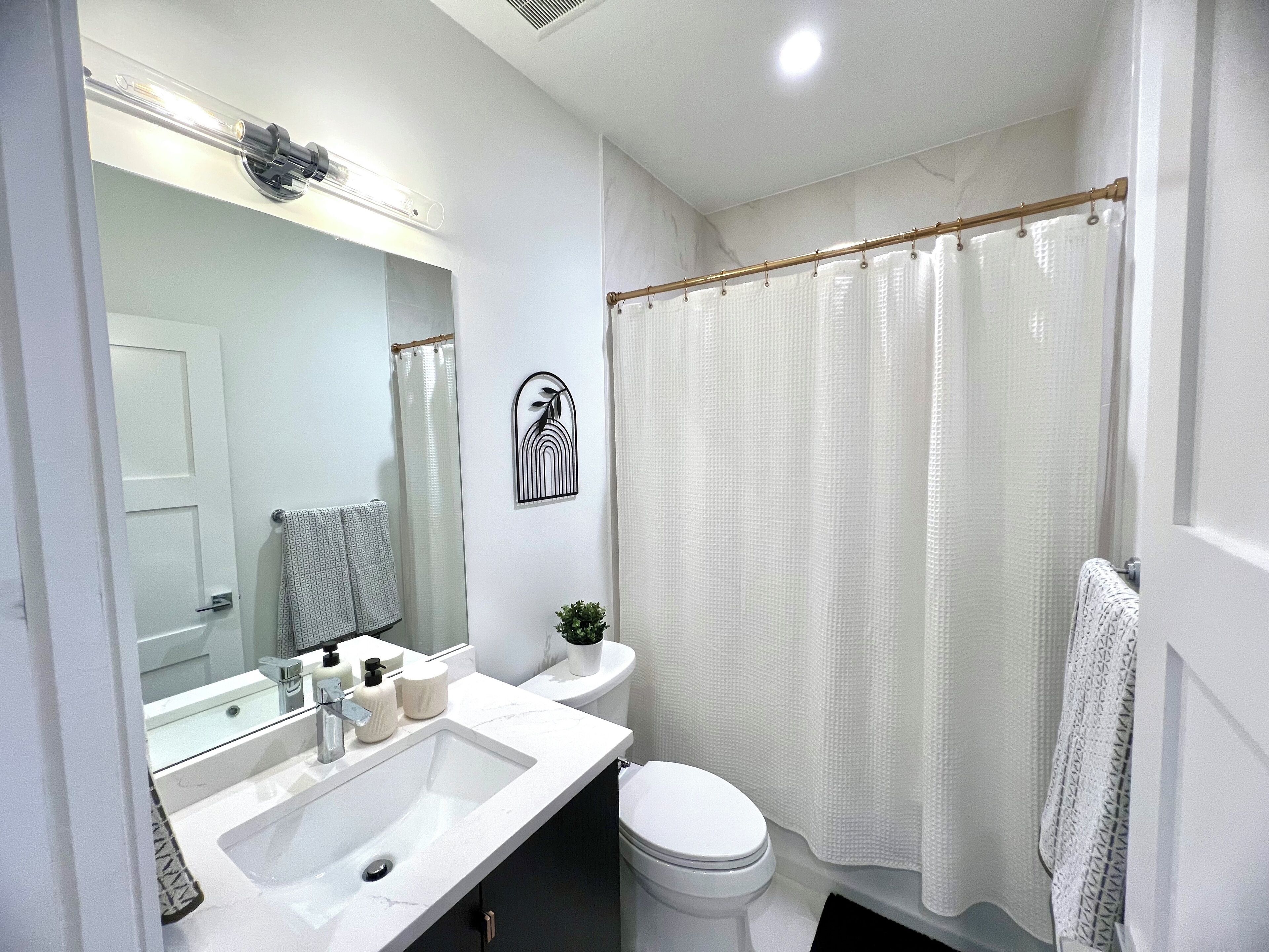 Een badkamer met een wit wastafel, toilet en douchegordijn.