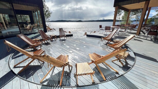 A deck with wooden lounge chairs arranged in a circle, overlooking a body of water. - Pistohiekka Resort (Puumala)