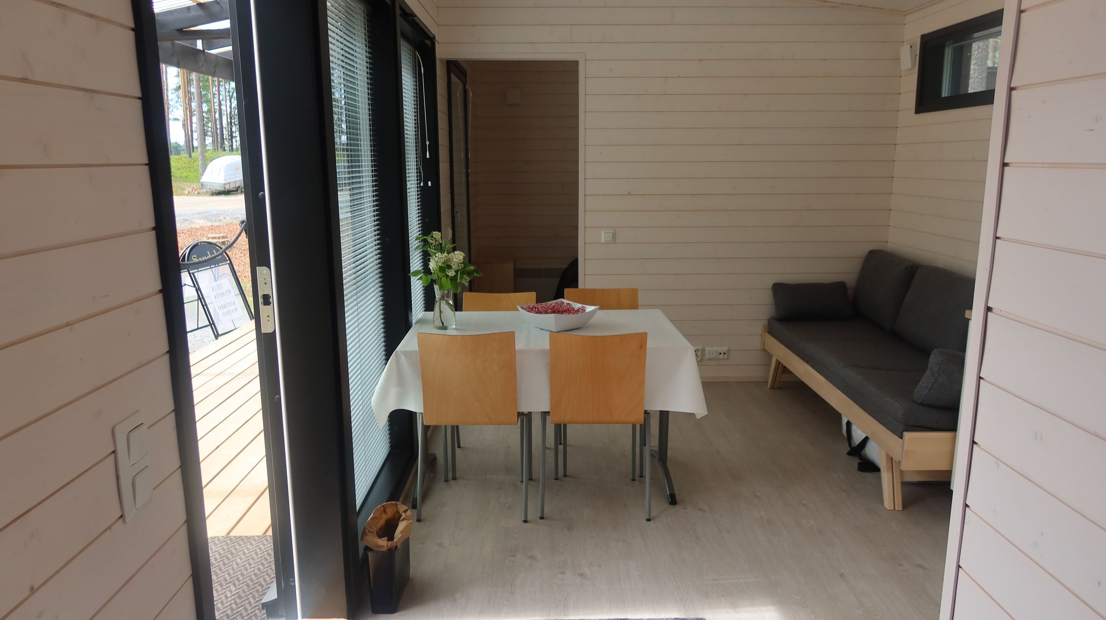Un petit espace extérieur aménagé pour les repas, à l’abri, avec une table et des chaises, un banc et un canapé.
