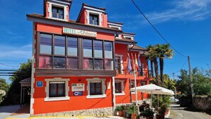 A red building with a sign reading "HOTEL Las Palmeras" and a wheelchair accessibility symbol. - Hotel Las Palmeras (Celorio)