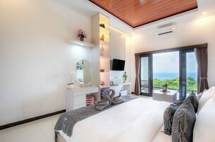 Un dormitorio moderno con una cama grande, un televisor, un aparador y vistas al exterior.