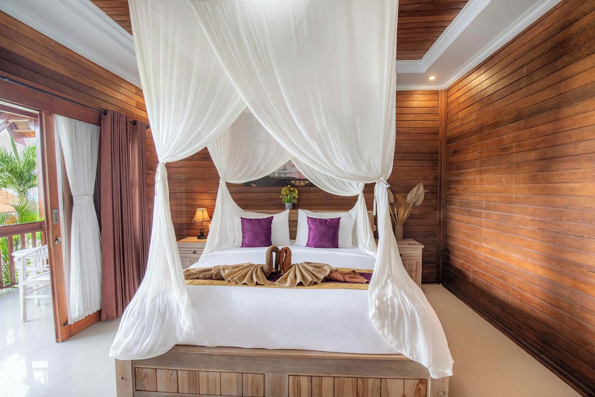 A large bed with a canopy, wooden walls, and a view of the outdoors.