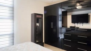 Une chambre à coucher avec un lit, une armoire, un téléviseur et un ventilateur de plafond.