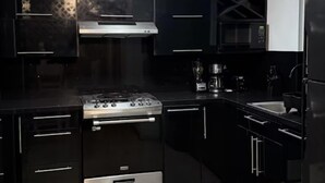 Une cuisine moderne avec des meubles de couleur noire, une cuisinière en acier inoxydable et un four à micro-ondes.
