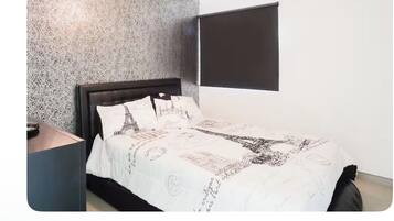 A bedroom with a bed, a nightstand, a window with blinds, and a textured wall.