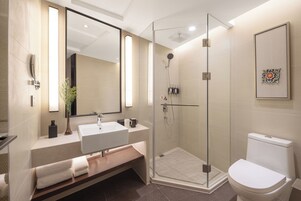 Un baño moderno con cabina de ducha de vidrio, un lavamanos blanco y un inodoro.