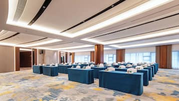 A conference room with multiple tables, ceiling lights, and a patterned carpet.