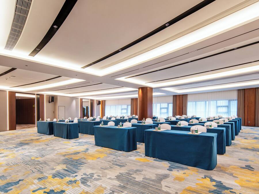 A conference room with multiple tables, ceiling lights, and a patterned carpet.