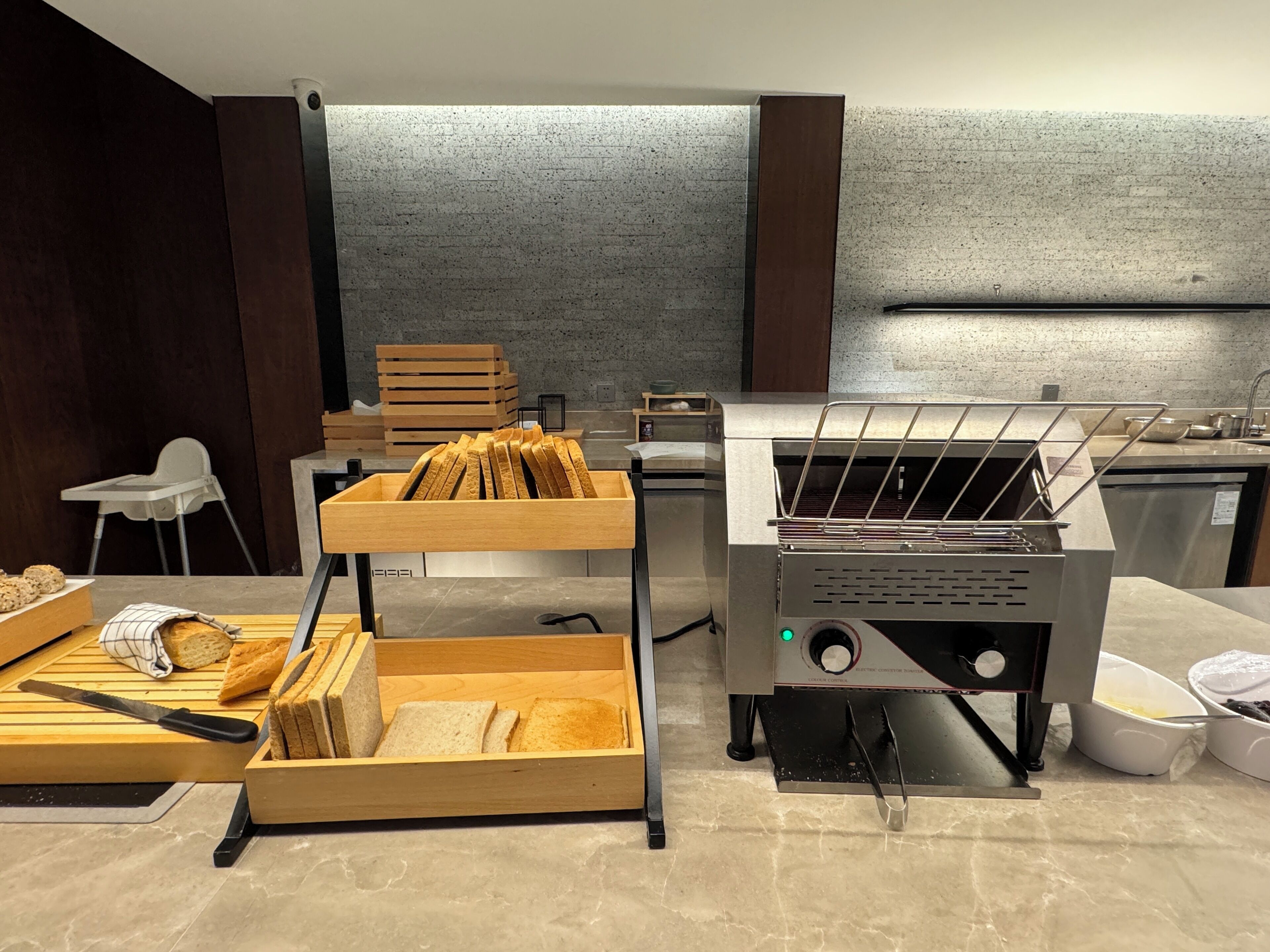 A kitchen area with a bread display, a bread slicer, and a commercial oven.