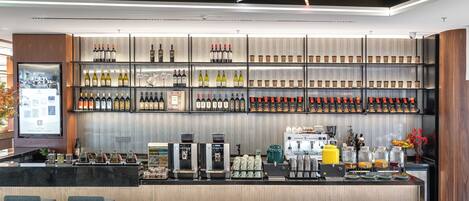 A modern bar area with a variety of wine bottles, coffee machines, and seating arrangements.