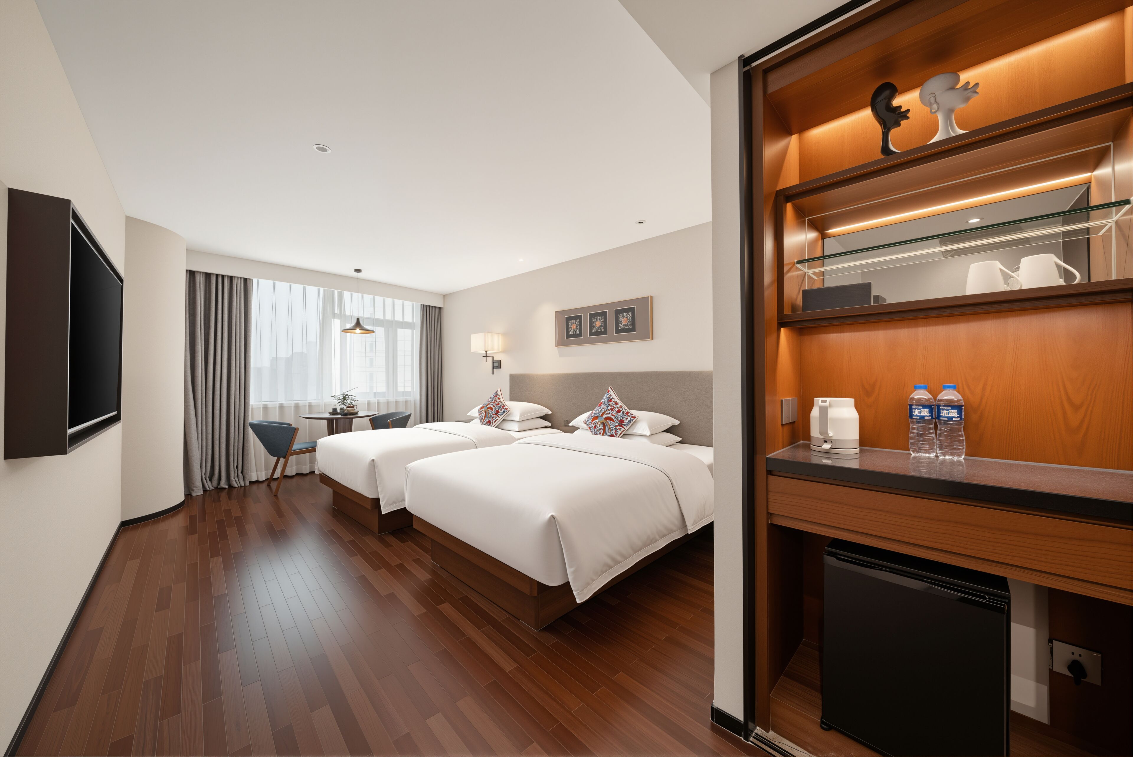Ein Hotelzimmer mit zwei Betten, einem Schreibtisch, einem Stuhl, einem Fernseher, einem kleinen Kühlschrank und einem Spiegel mit Holzrahmen.