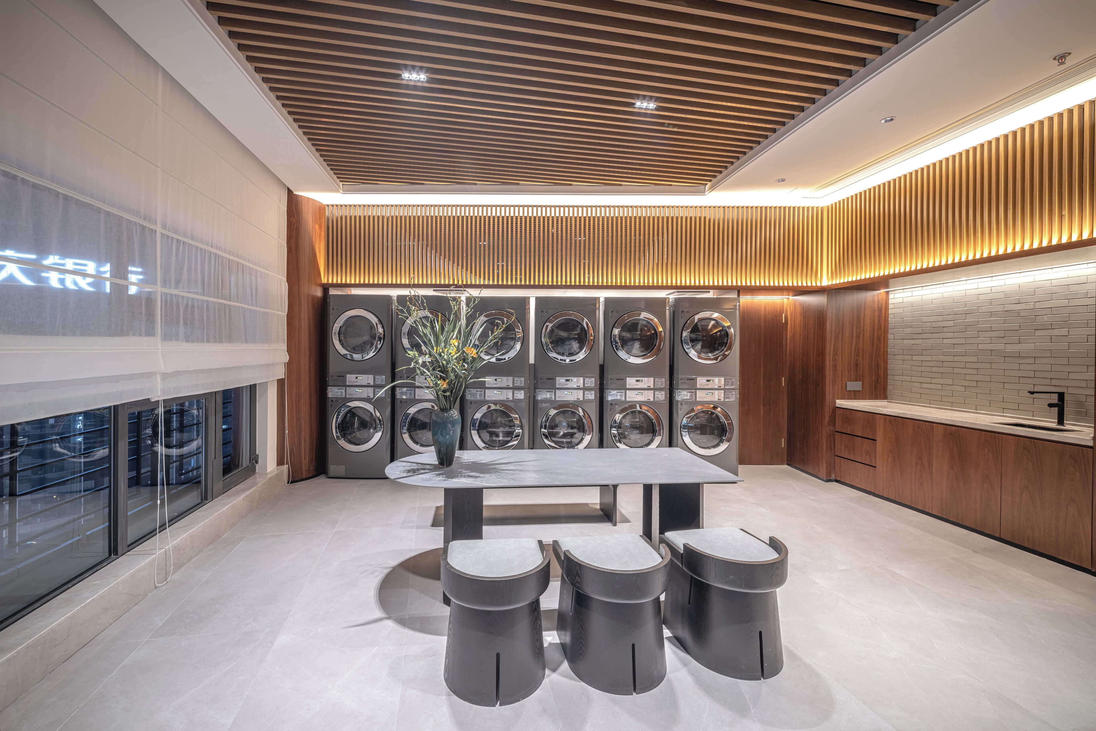 A modern kitchen with a central island, built-in appliances, and a wooden ceiling.