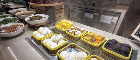 A buffet with various food items including dumplings, corn, and other dishes.