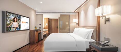 Habitación de hotel con cama, mesita de noche, lámpara y televisor montado en la pared.