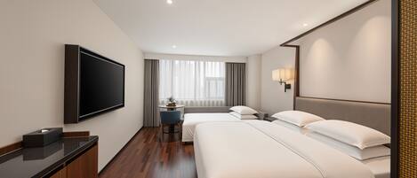 Quarto de hotel com televisão de tela plana, duas camas, uma escrivaninha e uma janela com cortinas.