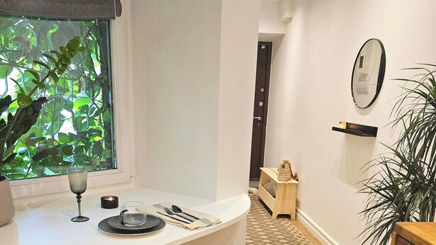 Une cuisine moderne avec un comptoir incurvé, une chaise en bois et une vue sur la verdure à l’extérieur.
