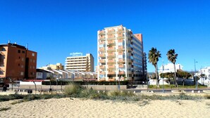 A coastal hotel with multiple floors, balconies, and a clear blue sky.