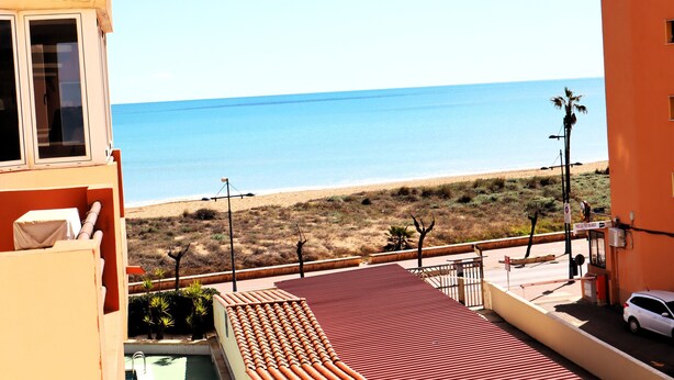 A view of a beach from a building with a red roof and a pool.