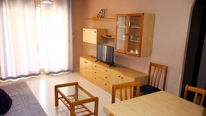 A compact living space with a dining area, a kitchenette, and a small TV on a wooden cabinet.