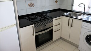 A kitchen with a gas stove, oven, sink, and washing machine.