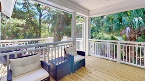 A covered porch with wicker furniture and a view of lush greenery.