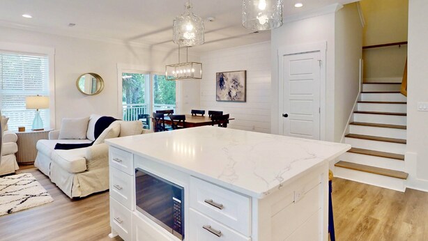 A spacious kitchen with a large island, pendant lights, and a view of the dining area.